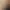 Eine Frau in einem weißen Bademantel lächelt und unterhält sich mit einer Person, von der nur der Rücken zu sehen ist, in einem Schönheitssalon mit Produkten im Hintergrund.