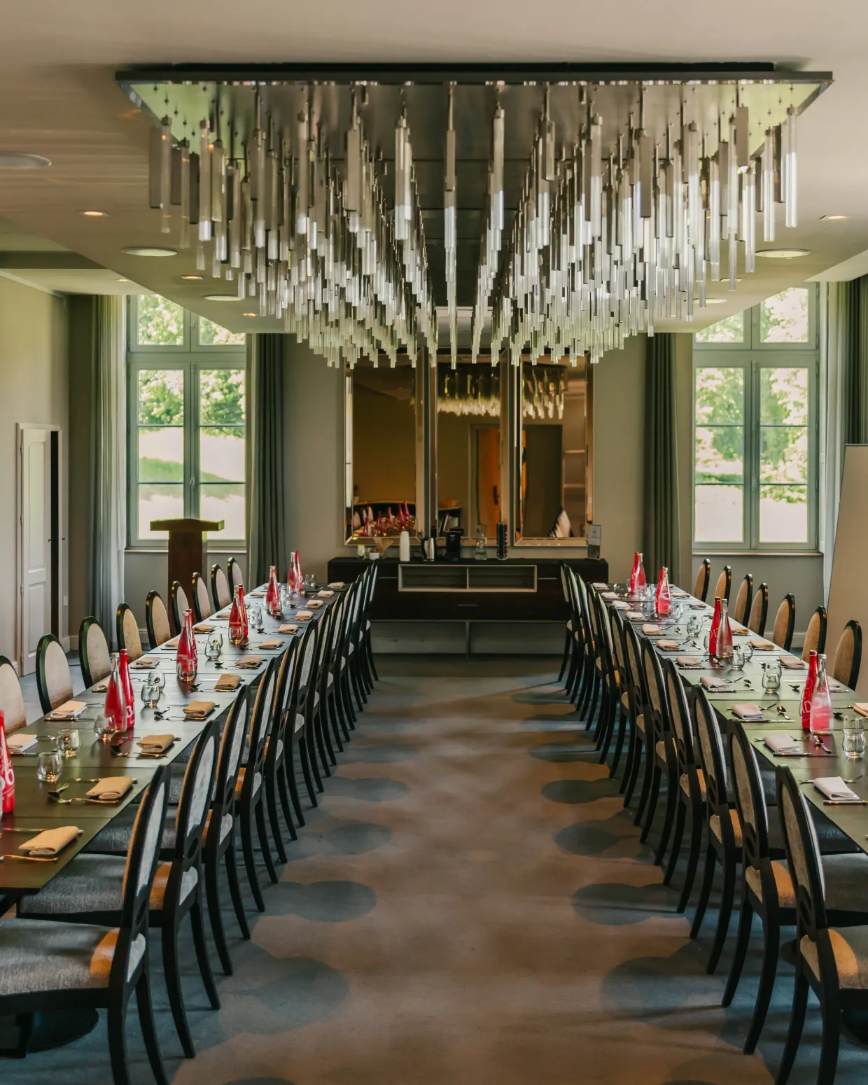 Salle de restaurant avec des tables dressées et des chandeliers suspendus au plafond