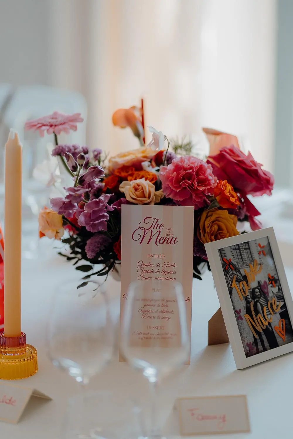 Une table décorée avec un bouquet de fleurs, des bougies, un menu et des cartes nominatives