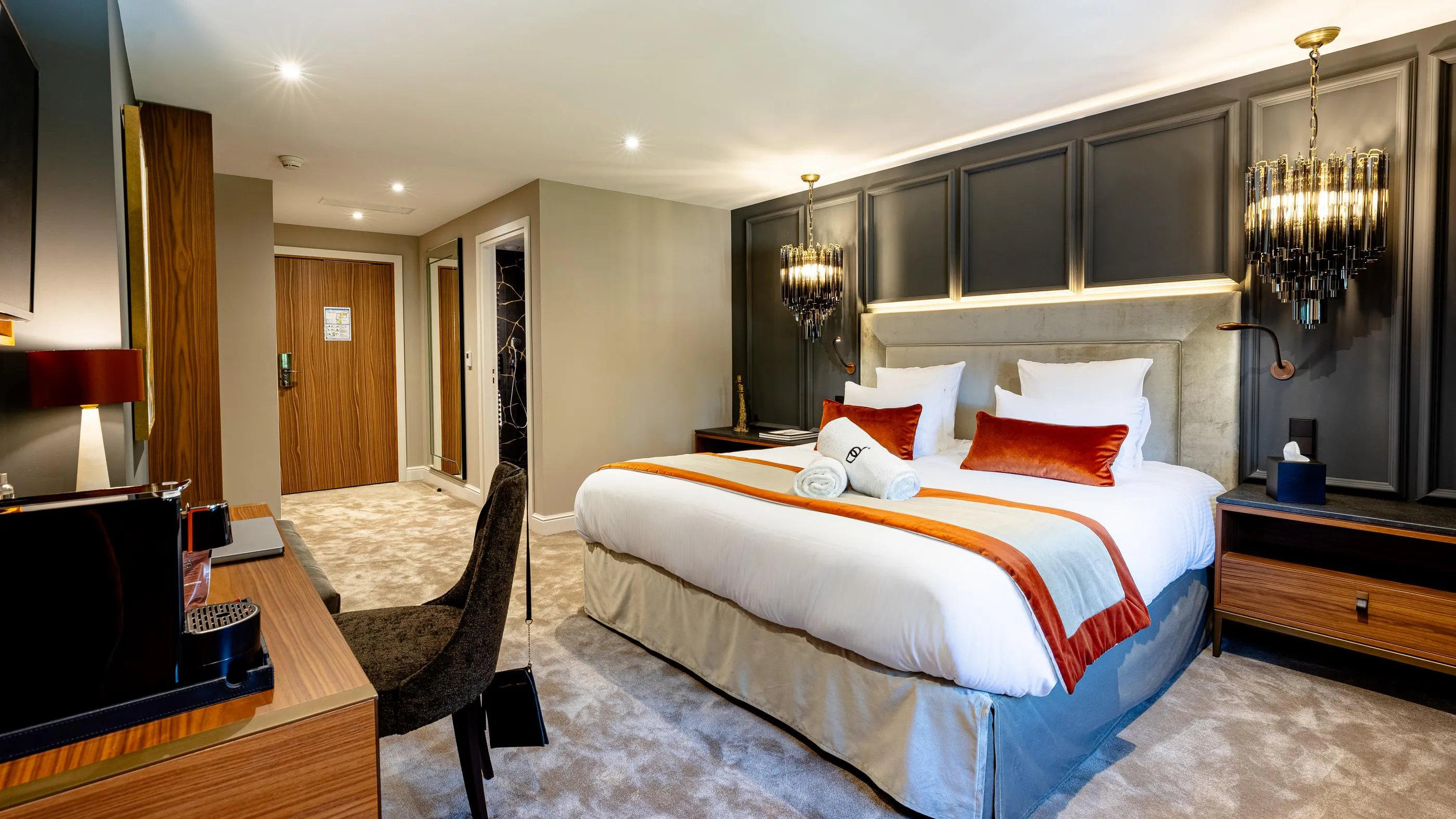 Chambre d'hôtel avec un lit double, une table de chevet, une chaise et un éclairage moderne