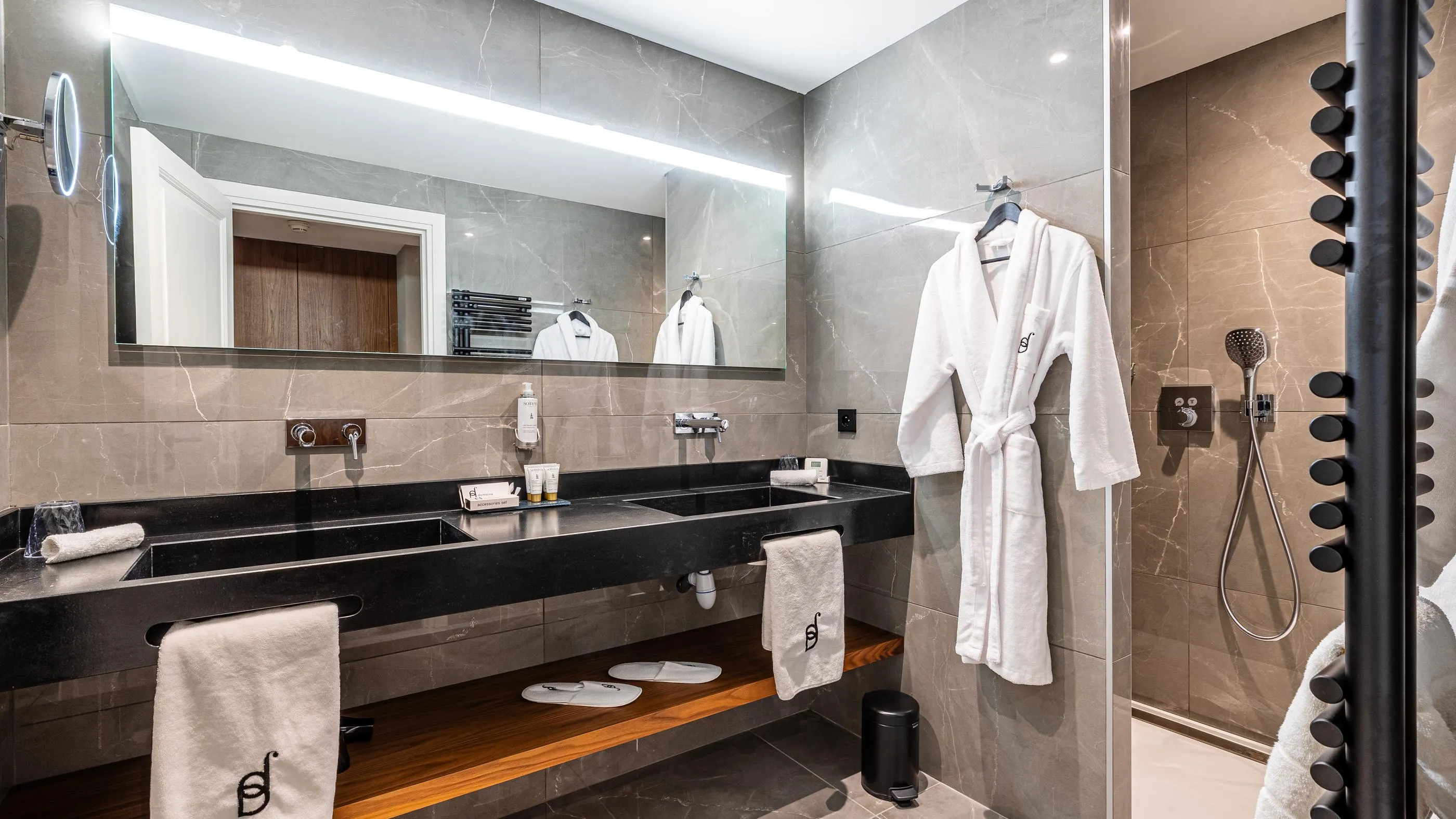 Moderne Badezimmer mit Doppelwaschbecken, Spiegel, weißen Bademänteln und italienischer Dusche