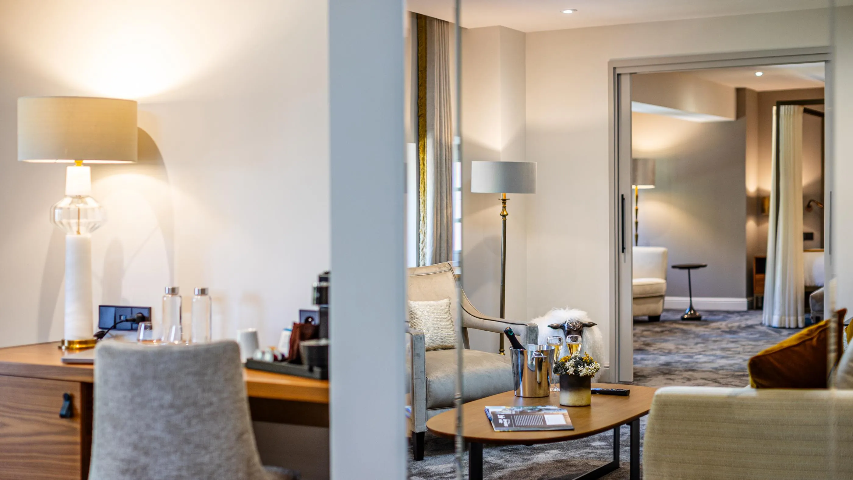 Hotel-Lounge mit Sesseln, Couchtisch, Lampen und Champagnerflaschen
