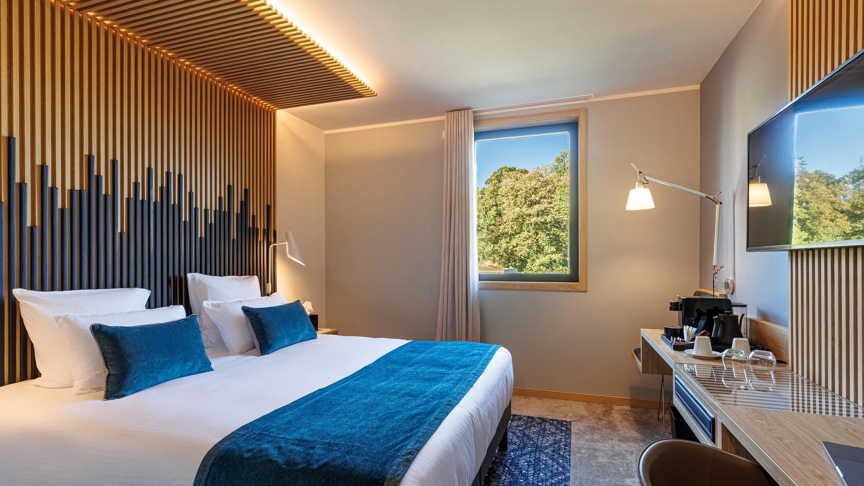 Chambre d'hôtel moderne avec un lit double, une table de chevet, une fenêtre et un écran plat