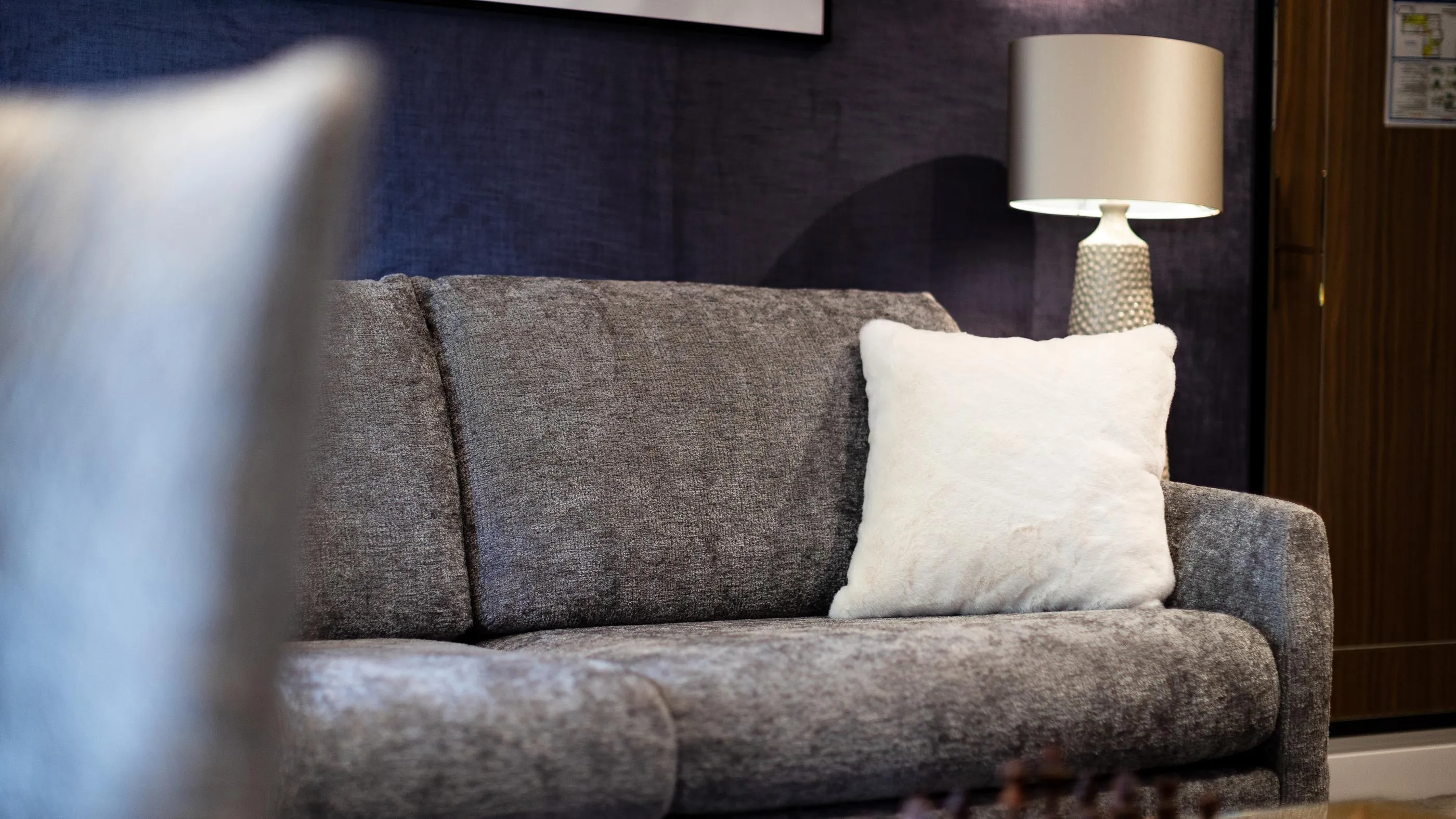 Canapé gris avec un coussin blanc et une lampe à abat-jour beige sur le côté