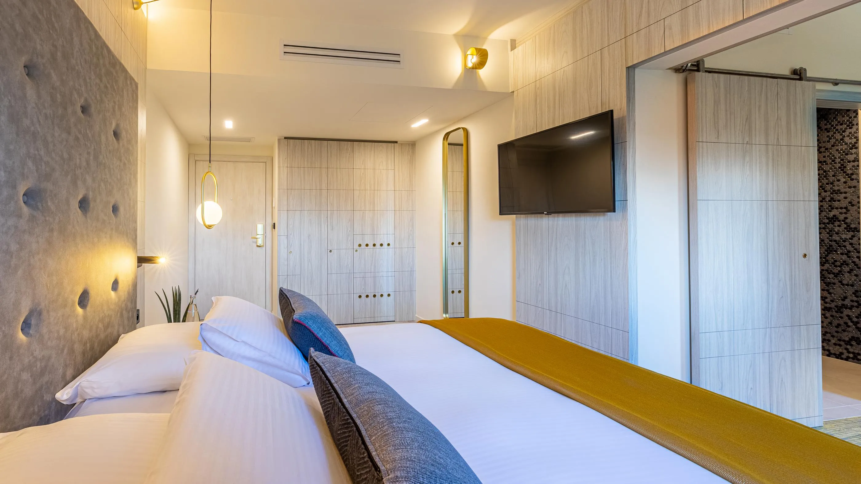 Chambre moderne avec deux lits simples, une télévision murale, des armoires intégrées et un éclairage doux
