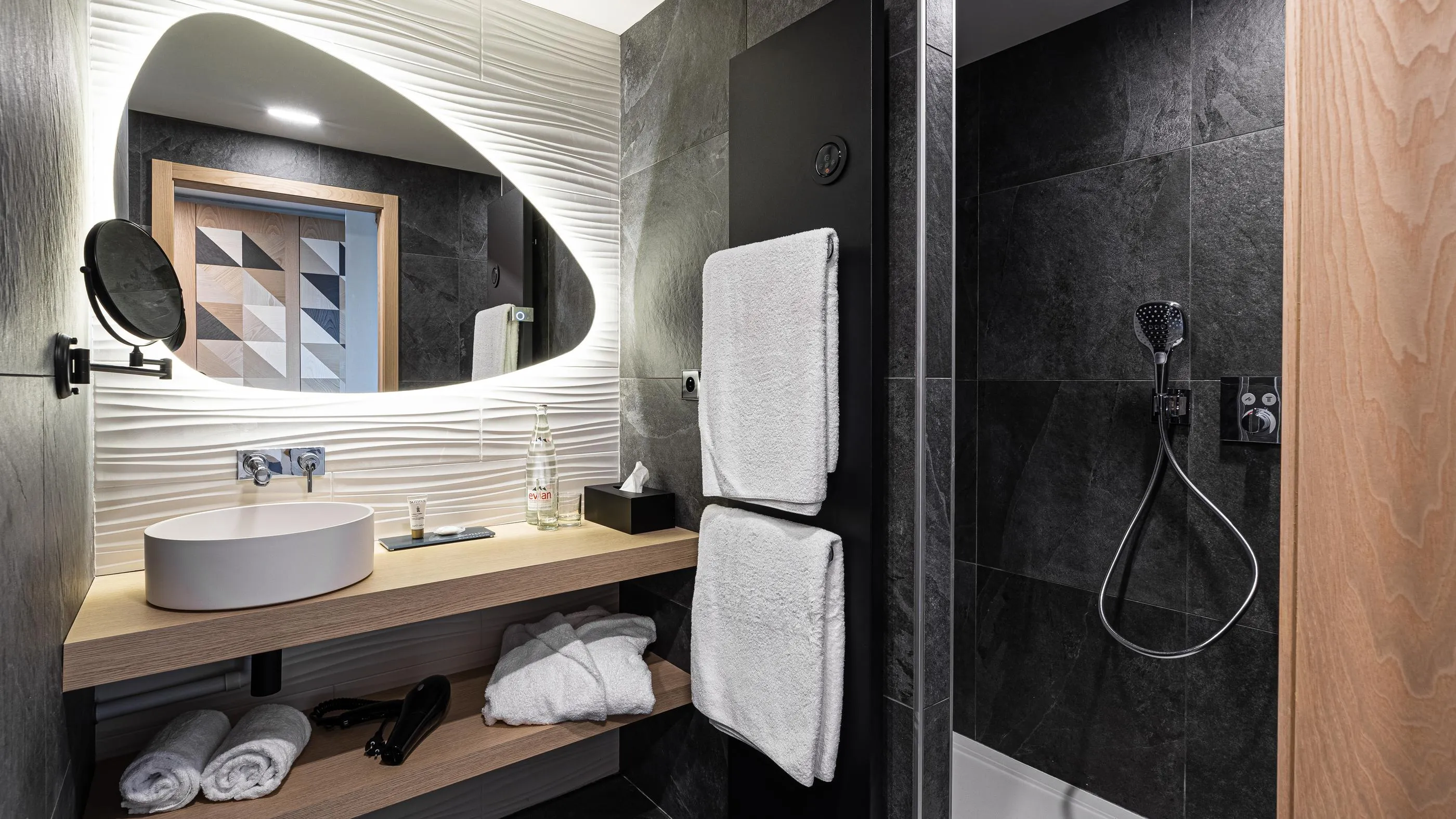 Salle de bain moderne avec lavabo, miroir ovale, serviettes et douche à main